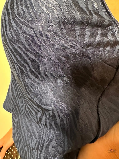Žena drží černou a stříbrnou kabelku k elegantnímu outfitu