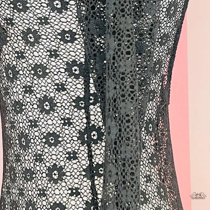 Detail černých krajkových šatů Victoria’s Secret s odhalenými zády na růžovém pozadí