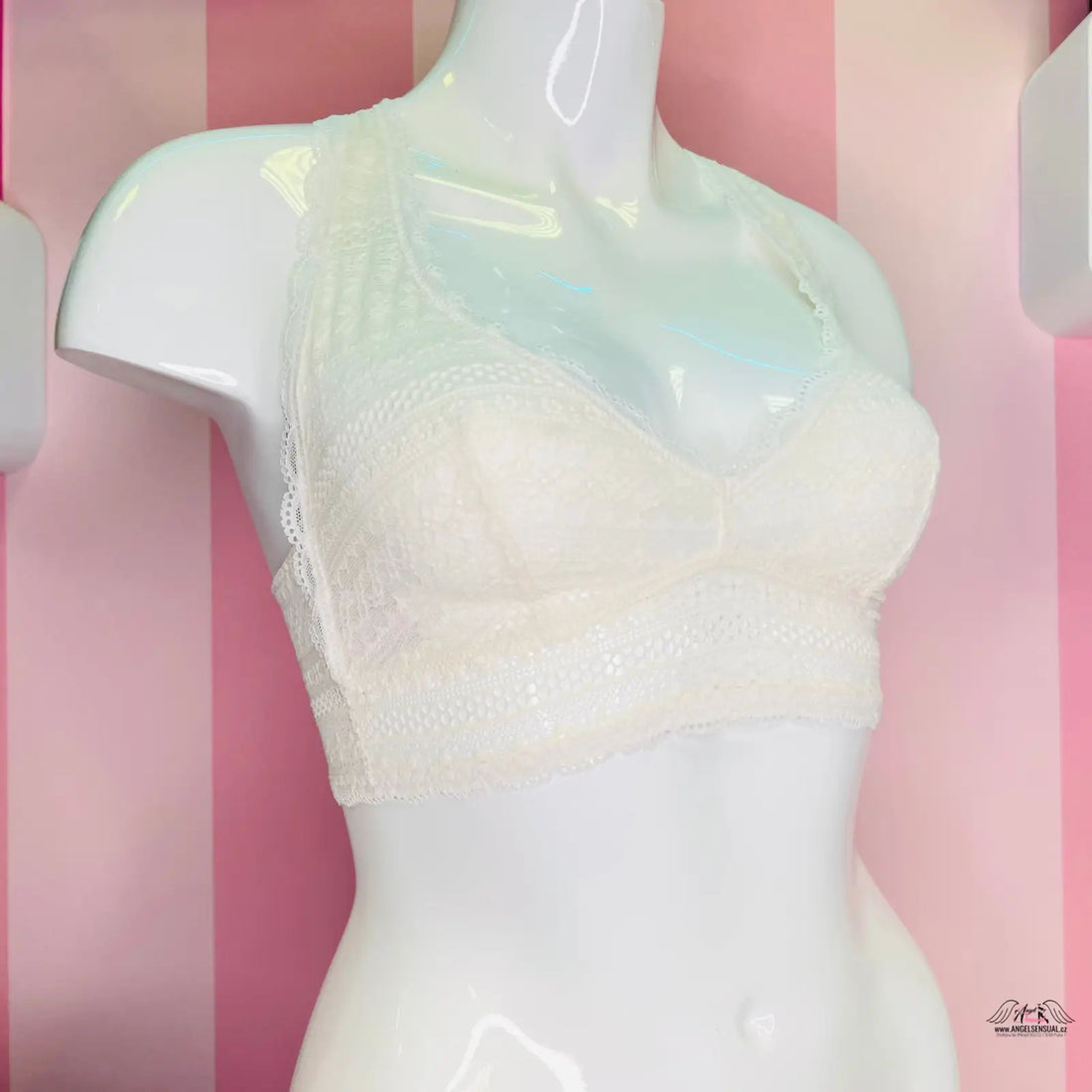 Manekýn s bílou lákavou krajkovou braletkou Victoria’s Secret na růžové pruhované stěně