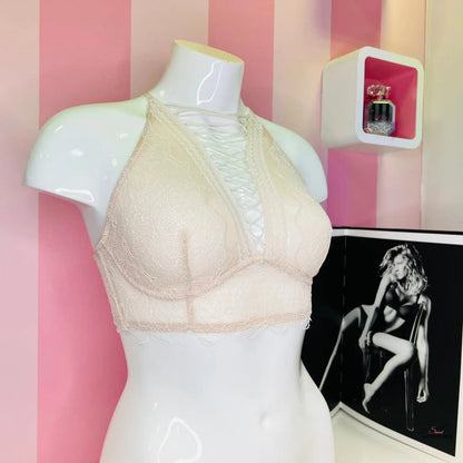 Arafovaná figurína s bílou podprsenkou Victoria’s Secret a překříženými ramínky na růžové pruhované zdi