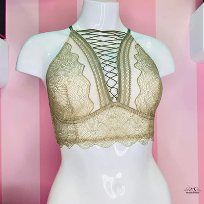Detailní pohled na zlatou podprsenku Victoria’s Secret s překříženými ramínky a výšivkou