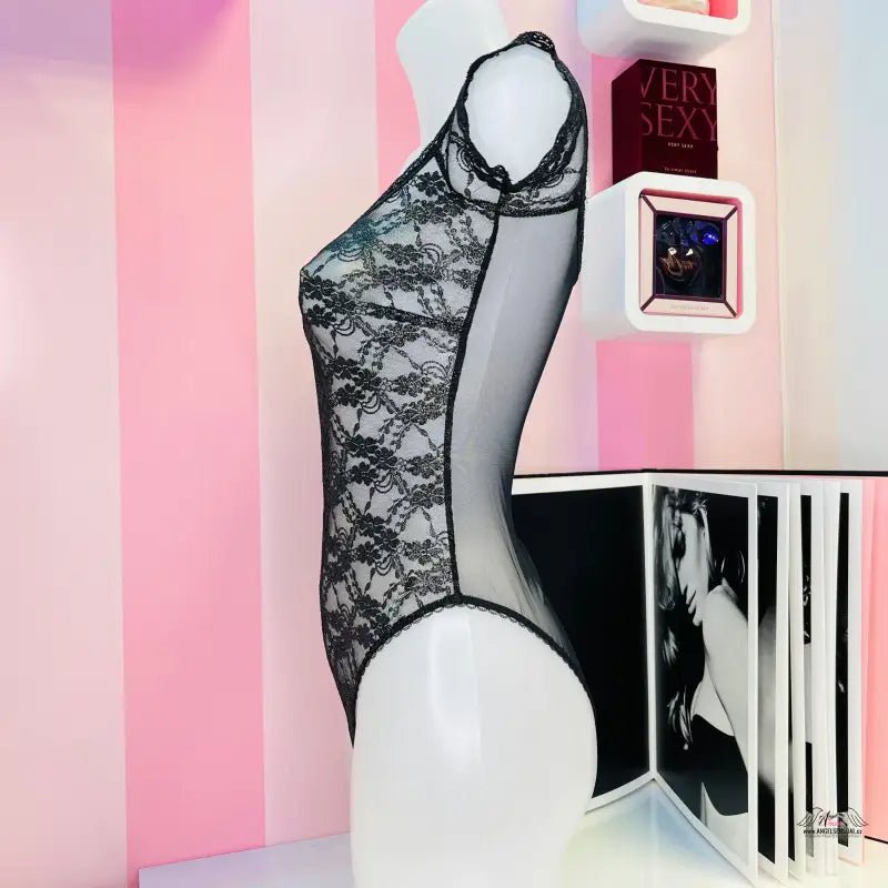 Manekýn v luxusním krajkovém plyšovém body Victoria’s Secret na růžovo-bílé stěně