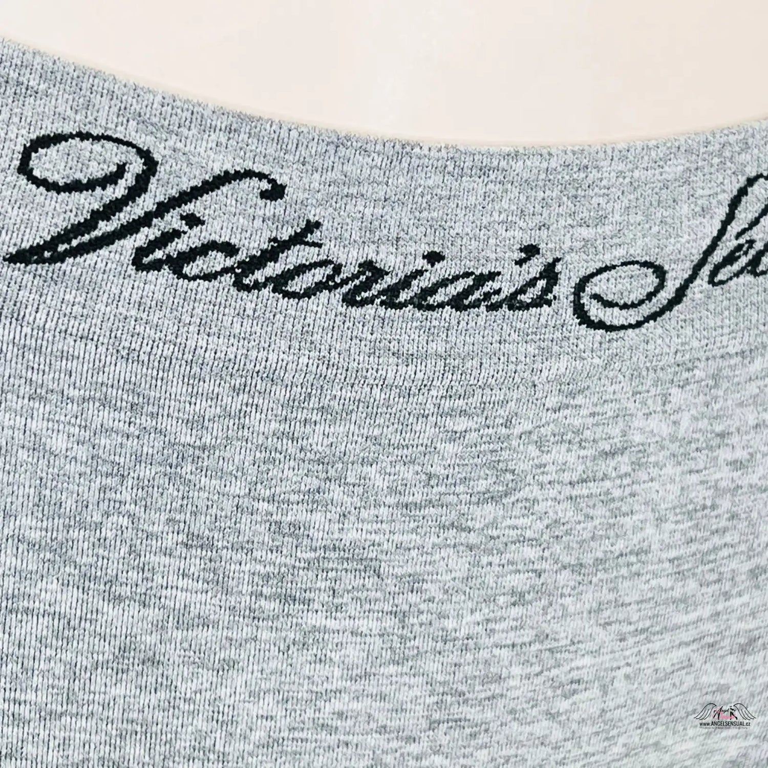 Žena v stylových šedých tangách Victoria’s Secret s černým nápisem láska